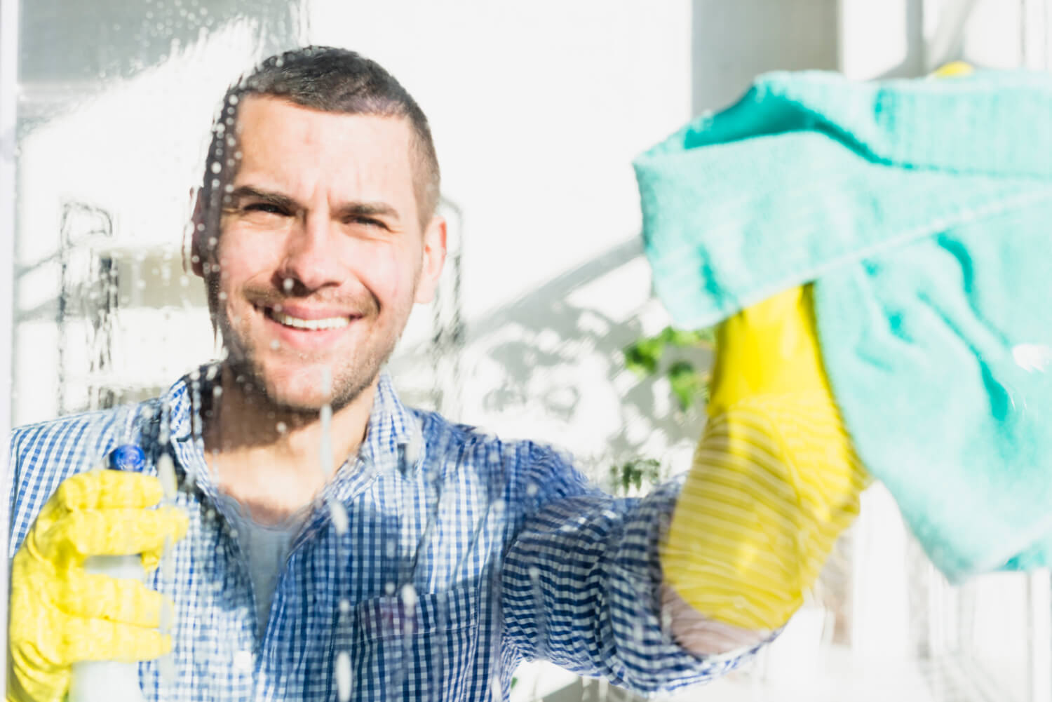 hombre sonriente limpiando una mampara de ducha